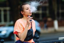 A young woman uses a vaping device